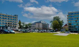 Nowoczesne budynki hotelowe i parking pełen samochodów na tle błękitnego nieba z chmurami.