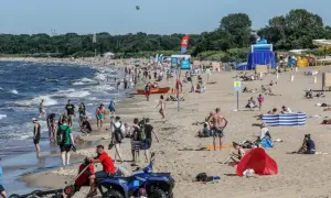 Tłum ludzi na piaszczystej plaży nad Bałtykiem w słoneczny dzień.