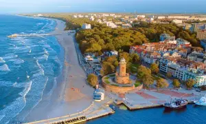 Widok z lotu ptaka na polski kurort nad morzem z latarnią morską, plażą i budynkami.