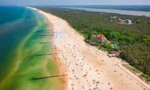 Widok z lotu ptaka na plażę w Łebie z turystami, morzem i lasem.