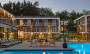 Nowoczesny hotel z basenem i leżakami, otoczony drzewami.