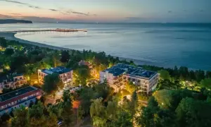 Widok z lotu ptaka na nadmorskie apartamenty i molo o zmierzchu.