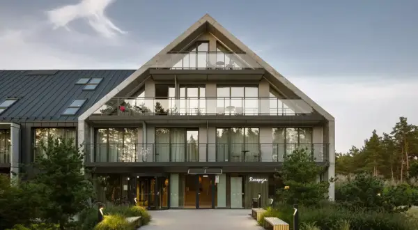 Nowoczesny budynek hotelowy Saltic Resort & Spa Łeba z betonową fasadą i przeszklonymi balkonami.