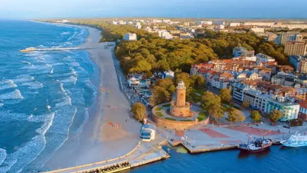 Widok z lotu ptaka na polski kurort nad morzem z latarnią morską, plażą i budynkami.