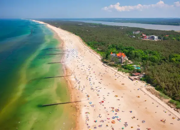 Widok z lotu ptaka na plażę w Łebie z turystami, morzem i lasem.