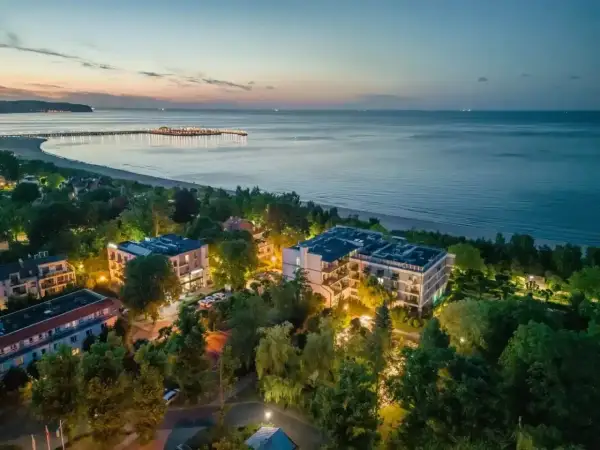 Widok z lotu ptaka na nadmorskie apartamenty i molo o zmierzchu.